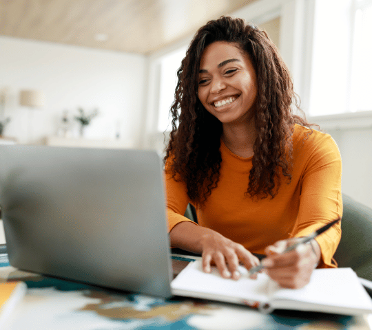 Young Adult Female Taking Notes While Learning on Laptop at Home