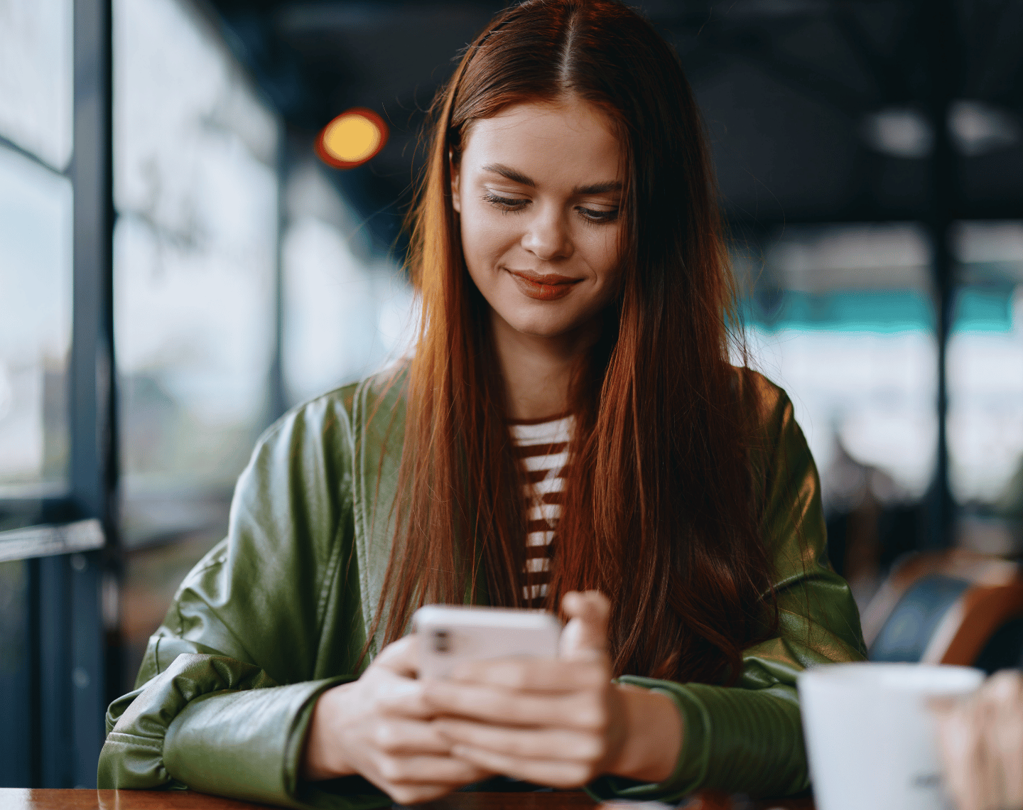 Young Woman Looking at Phone in Coffee Shop
